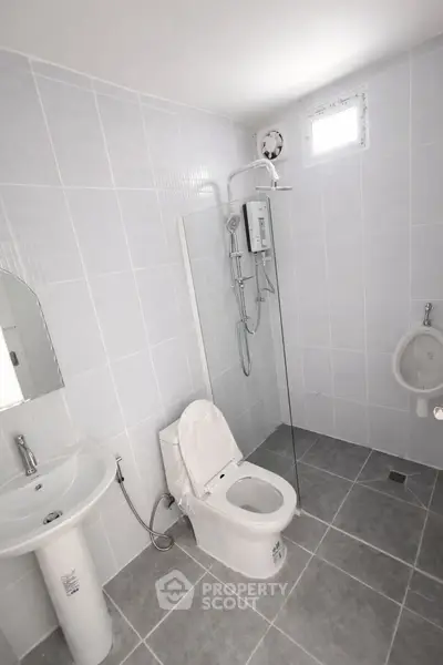 Modern bathroom with sleek fixtures and minimalist design, featuring a shower and urinal.