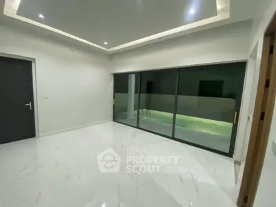 Modern interior with marble flooring and sliding glass doors leading to a pool view.