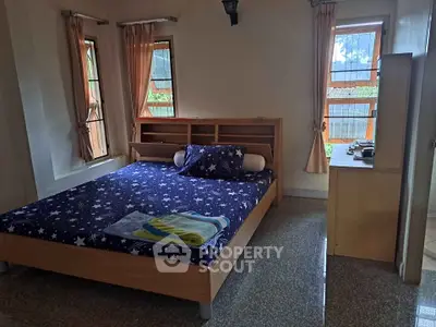 Cozy bedroom with starry bedding and natural light from two windows, perfect for relaxation.