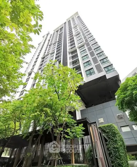 Modern high-rise building with lush greenery and sleek architectural design.