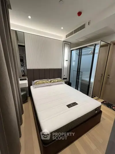 Modern bedroom with stylish decor and glass wardrobe doors, featuring a comfortable bed and elegant lighting.