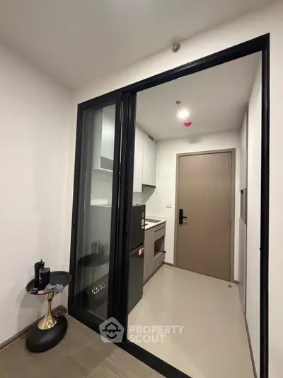 Modern compact kitchen with sleek design and sliding glass door in a contemporary apartment.