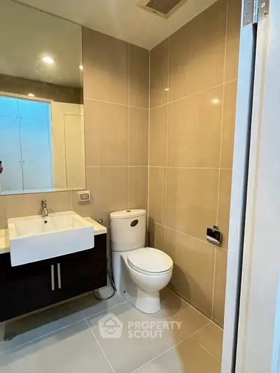 Modern bathroom with sleek fixtures and neutral tiles, featuring a stylish vanity and toilet.
