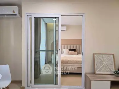 Modern apartment with sliding glass doors leading to a cozy bedroom, featuring stylish decor and air conditioning.