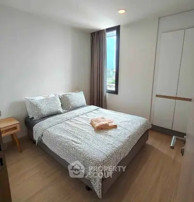 Cozy bedroom with large window and modern furnishings in a bright apartment.