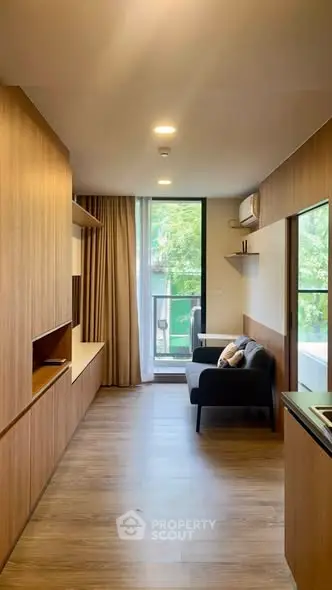 Modern living room with wooden flooring and large window offering natural light.