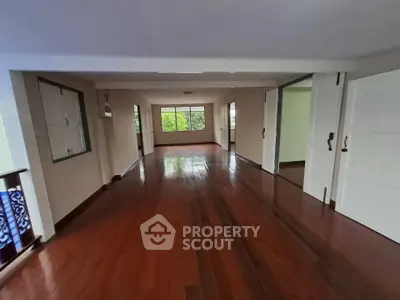 Spacious empty room with polished wooden floors and large windows