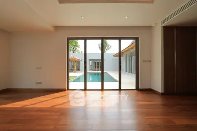 Spacious living room with wooden flooring and pool view, perfect for modern living.