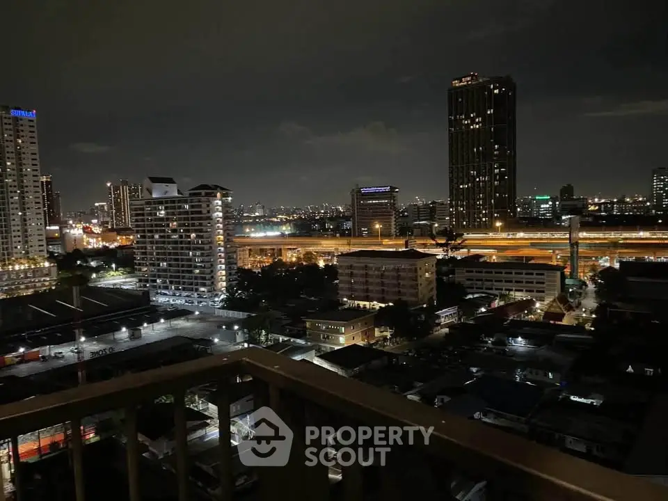 Stunning cityscape night view from a high-rise balcony overlooking urban skyline and illuminated highways.