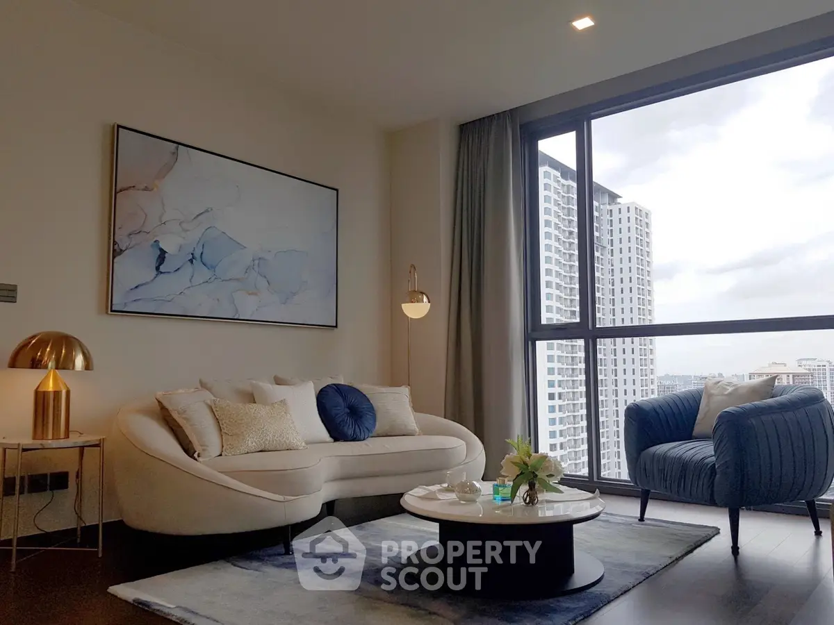 Modern living room with stylish furniture and large window view in high-rise apartment.