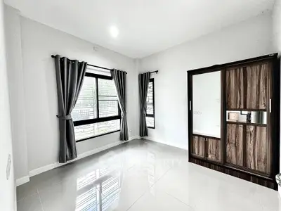 Spacious bedroom with large windows and modern wardrobe in a bright, minimalist design.