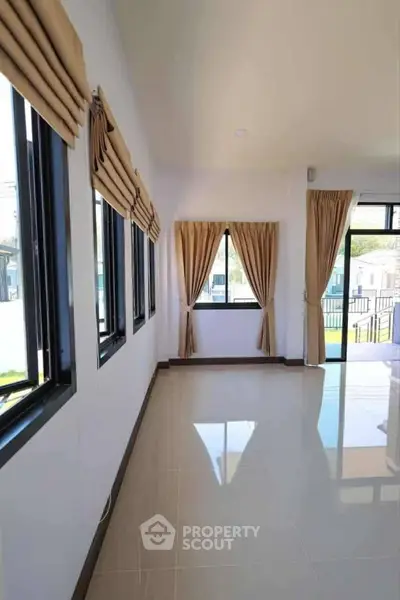 Spacious sunlit room with large windows and elegant drapes, perfect for modern living.