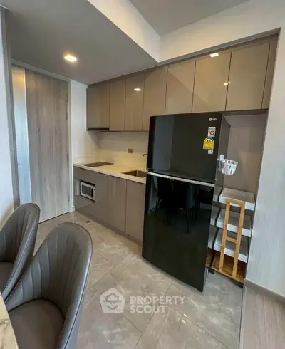 Modern kitchen with sleek cabinets and black fridge in stylish apartment