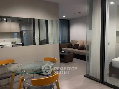Modern open-plan living room with glass dining table and cozy seating area