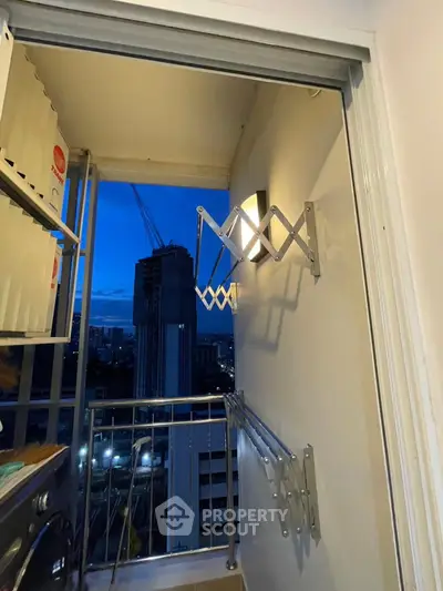 Compact balcony with city view and modern drying rack at dusk