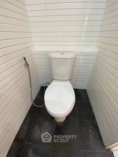 Compact bathroom with modern toilet and white tiled walls.