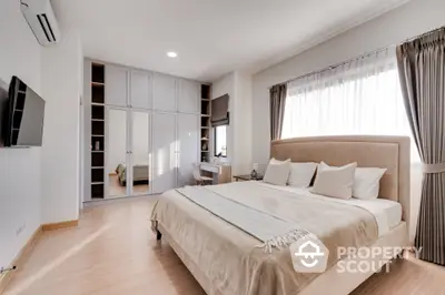 Spacious bedroom with large bed, built-in wardrobes, and modern design, featuring hardwood floors and ample natural light for a serene living space.