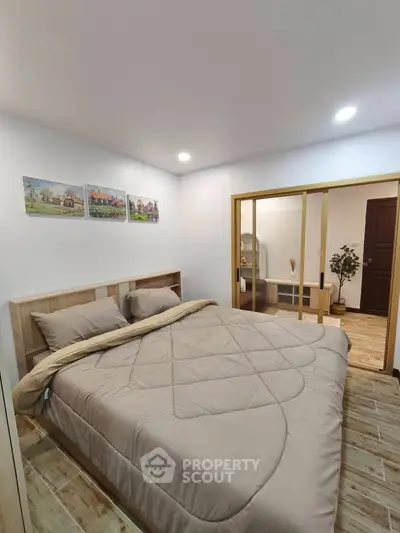 Cozy bedroom with modern decor and wooden flooring, featuring a comfortable bed and stylish artwork.