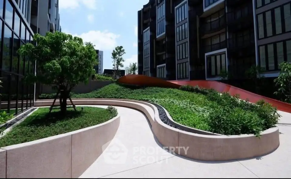 Modern apartment complex with lush landscaped garden and contemporary architecture.