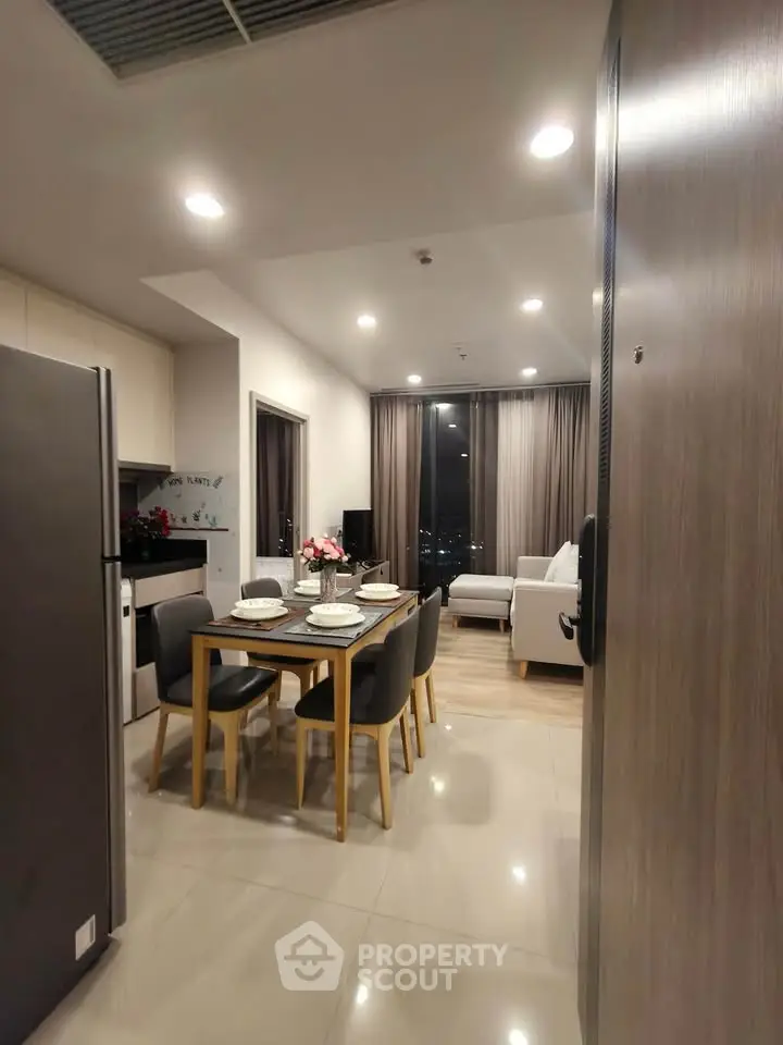 Modern open-layout living and dining area with city view, featuring sleek furniture and ambient lighting.