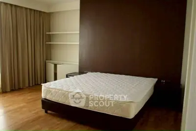 Spacious bedroom with wooden flooring and modern design.