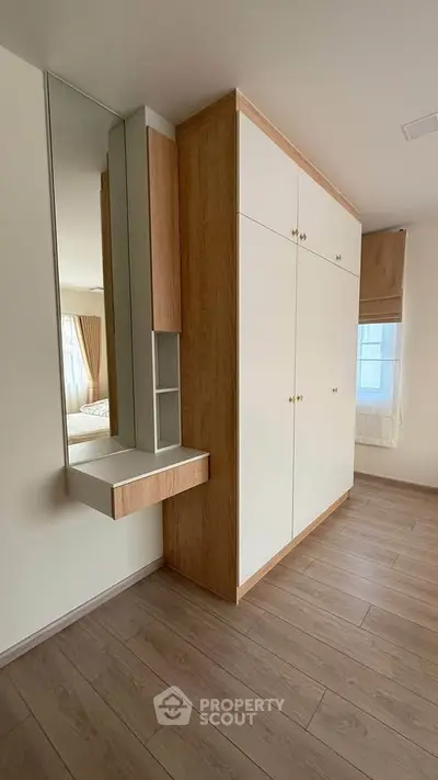 Spacious bedroom with built-in wardrobe and elegant wooden flooring