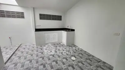 Spacious tiled utility area with sink and counter, ideal for laundry or storage.