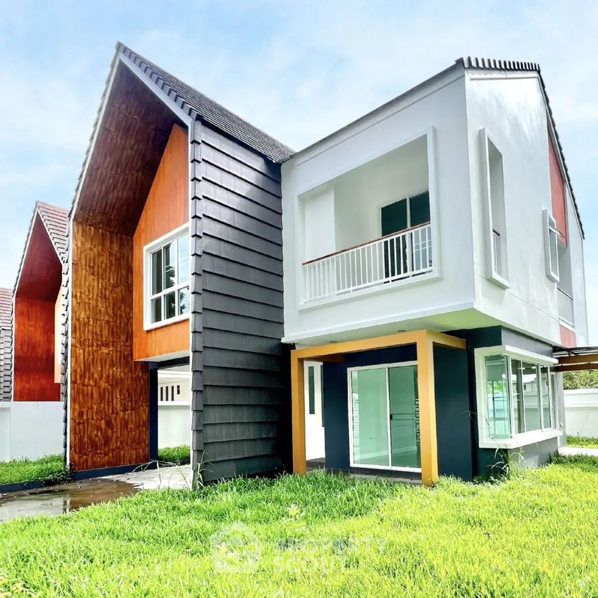 Modern two-story house with unique architectural design and lush green lawn.