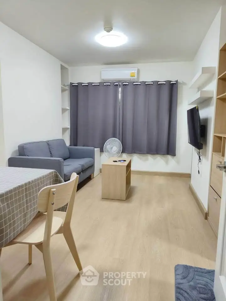 Modern living room with cozy sofa, wall-mounted TV, and dining area in a stylish apartment.