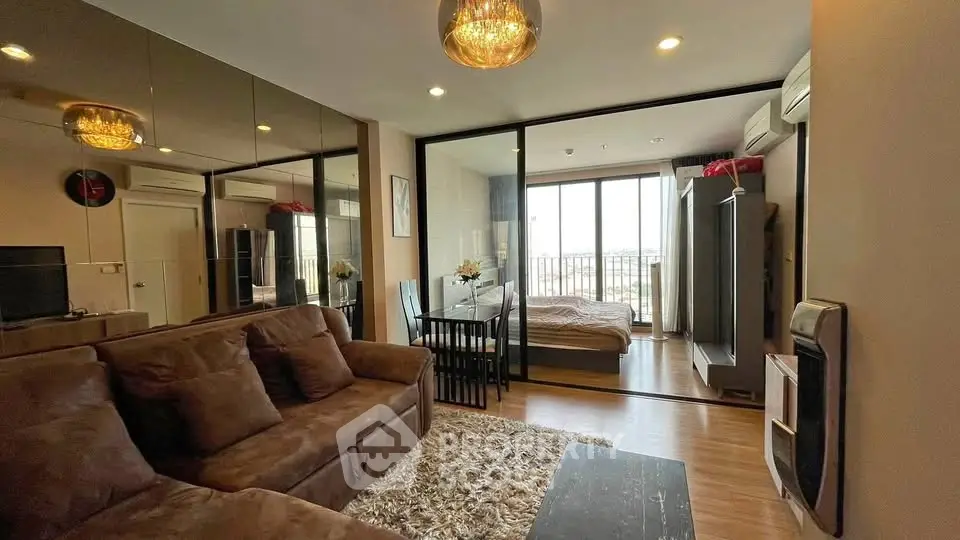 Modern living room with cozy sofa and adjacent bedroom featuring large windows and balcony view.