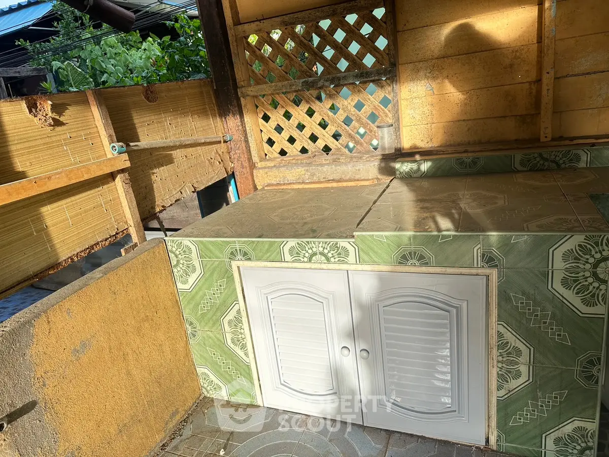 Charming outdoor kitchen area with tiled counter and rustic wooden accents, perfect for entertaining.