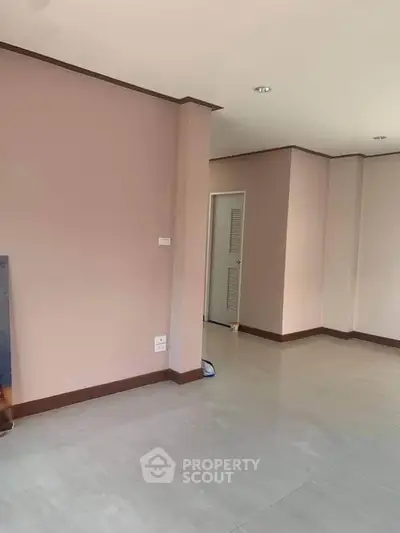 Spacious empty room with light pink walls and tiled flooring, ready for customization.
