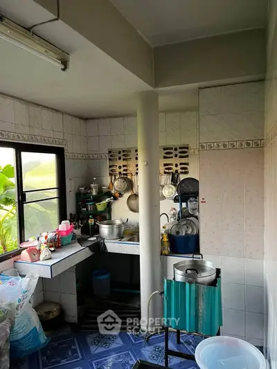 Charming kitchen with natural light and traditional decor, featuring a cozy cooking area and tiled flooring.