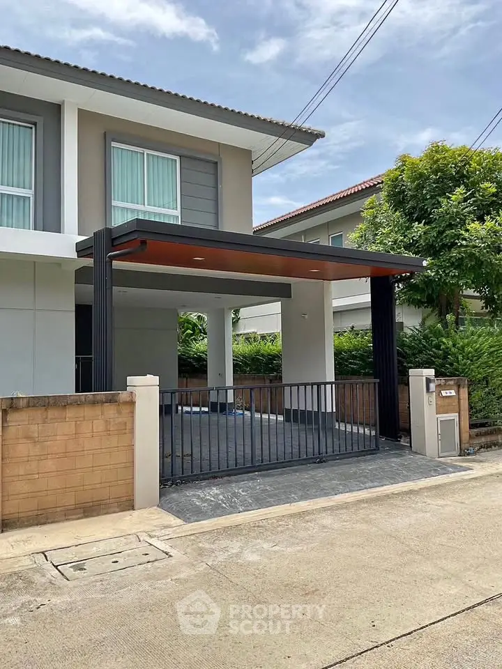 Modern two-story house with sleek carport and gated driveway in suburban neighborhood.