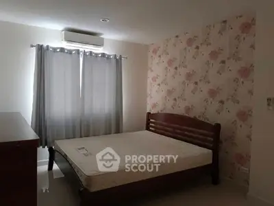 Cozy bedroom with floral wallpaper and air conditioning, perfect for relaxation.
