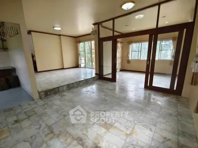 Spacious open-plan living area with marble flooring and large windows.
