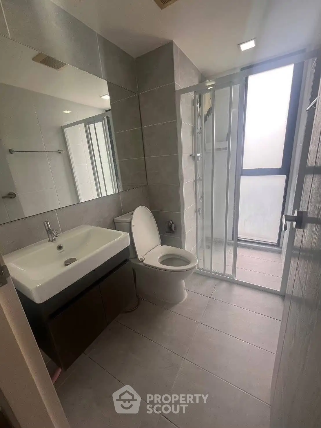 Modern bathroom with sleek fixtures and glass shower enclosure in contemporary apartment.