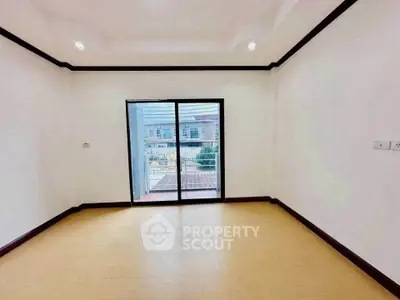 Spacious empty room with large window and balcony view in modern apartment.