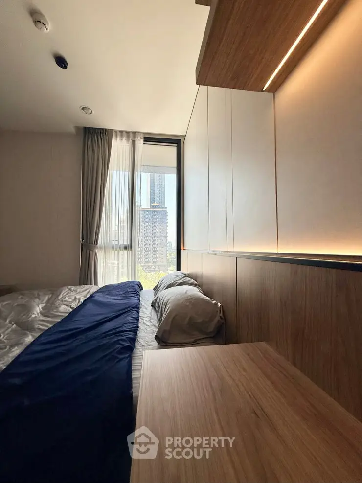 Modern bedroom with large window and wooden accents in urban apartment
