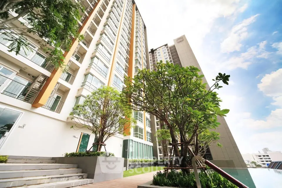 Modern high-rise building with lush greenery and clear blue sky, perfect for urban living.