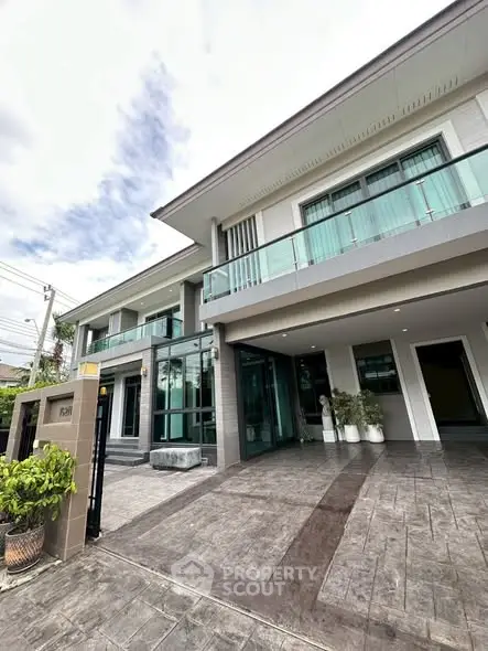 Modern two-story house with glass balcony and spacious driveway