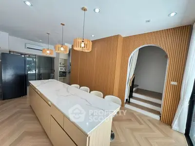 Modern kitchen with marble island, wooden accents, and stylish lighting in a contemporary home.