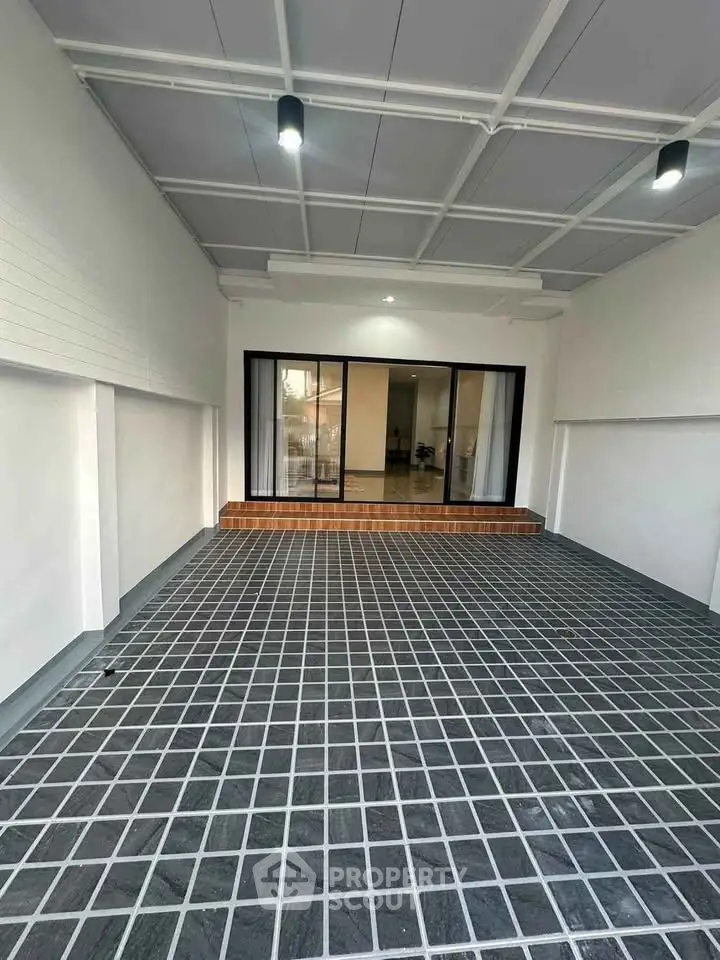 Spacious covered parking area with modern tiled flooring and glass sliding doors.