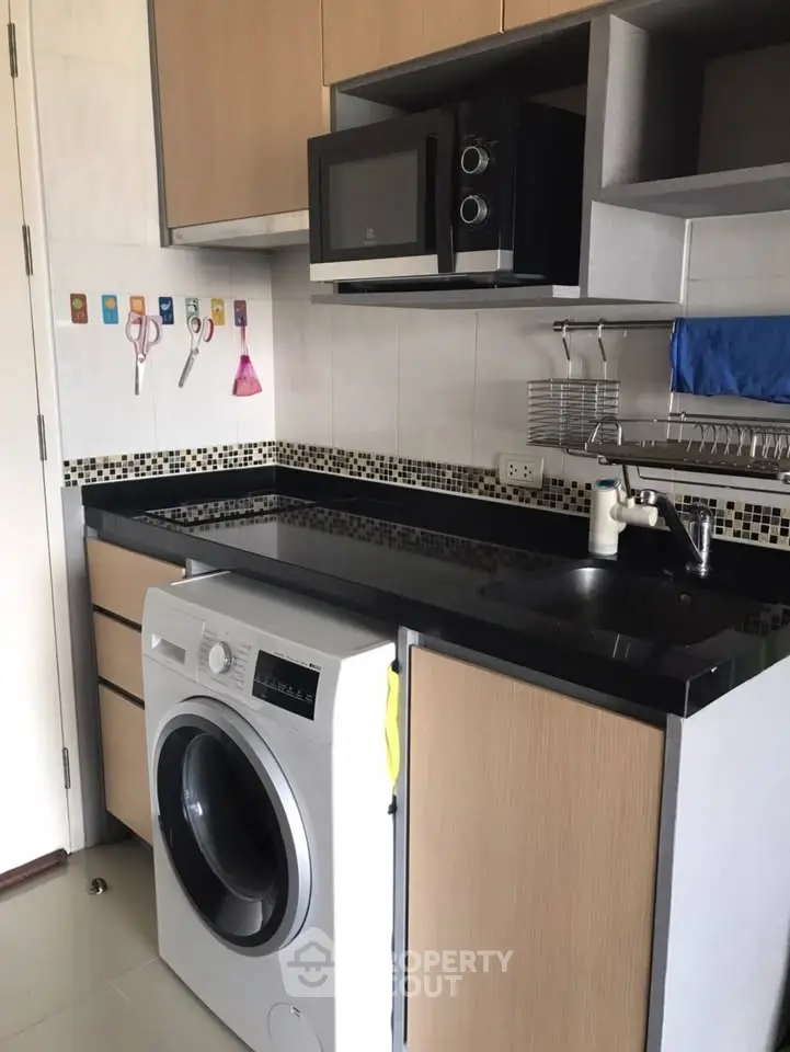 Modern kitchen with washing machine and microwave in compact layout