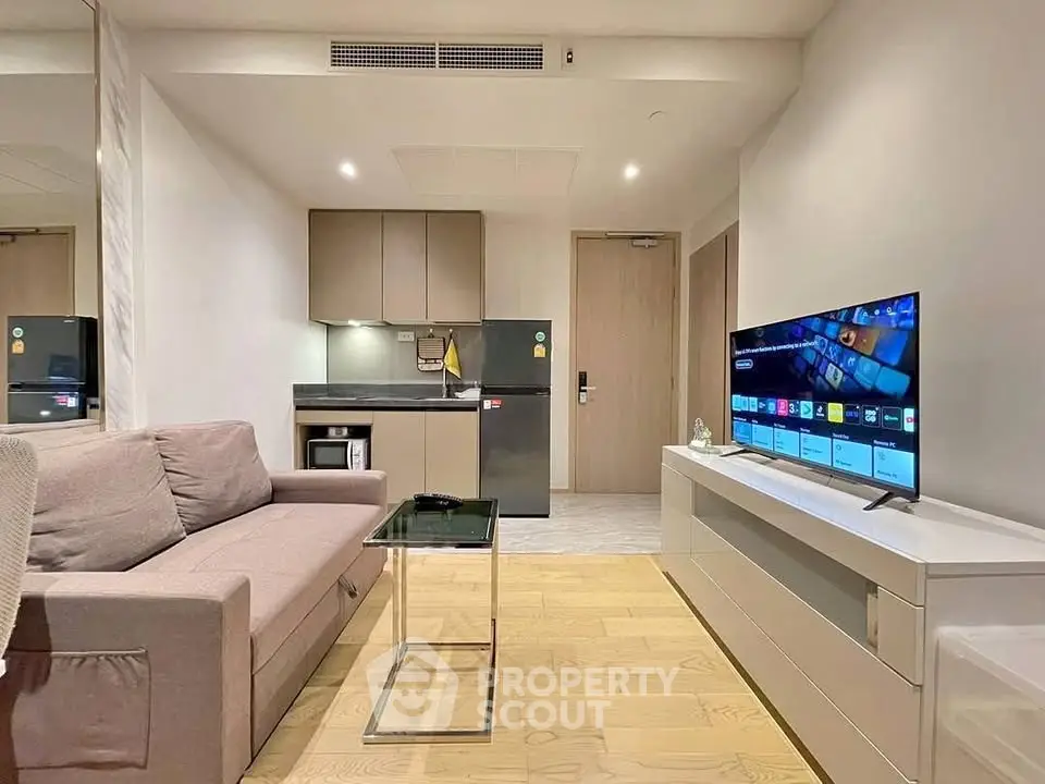 Modern living room with sleek furniture and smart TV, open kitchen layout, ideal for urban living.