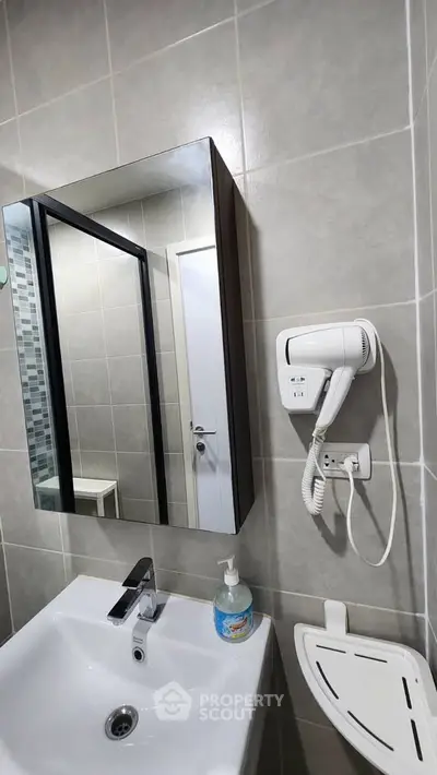 Modern bathroom with sleek sink, mirror cabinet, and wall-mounted hairdryer.