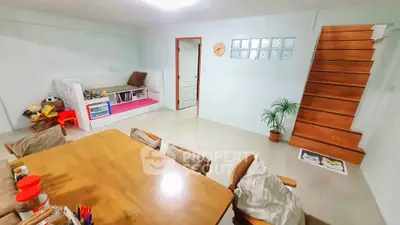 Spacious family room with wooden staircase and cozy dining area