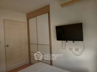 Cozy bedroom with wall-mounted TV and sliding closet doors, perfect for modern living.