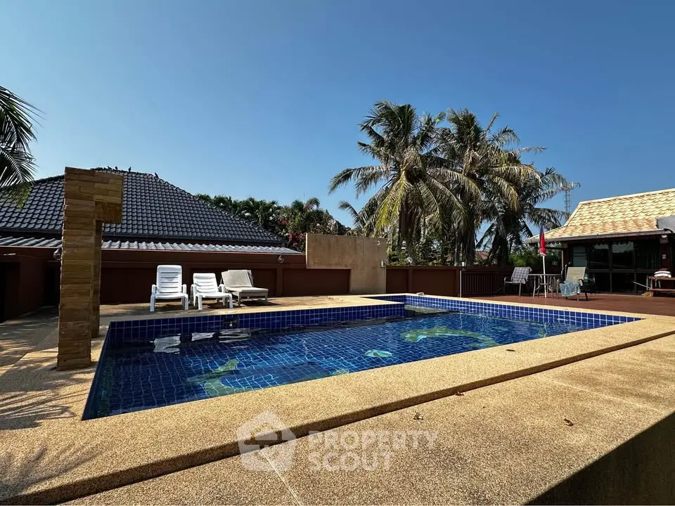 Luxurious outdoor pool area with tropical palm trees and sun loungers, perfect for relaxation and leisure.