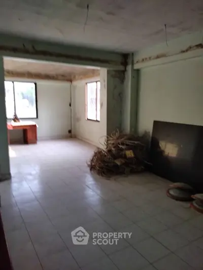 Spacious interior with potential for renovation, featuring large windows and tiled flooring.